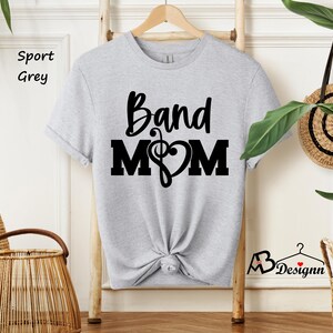 May include: A grey t-shirt with the text "Band Mom" in black lettering. A musical note and heart are included in the design.