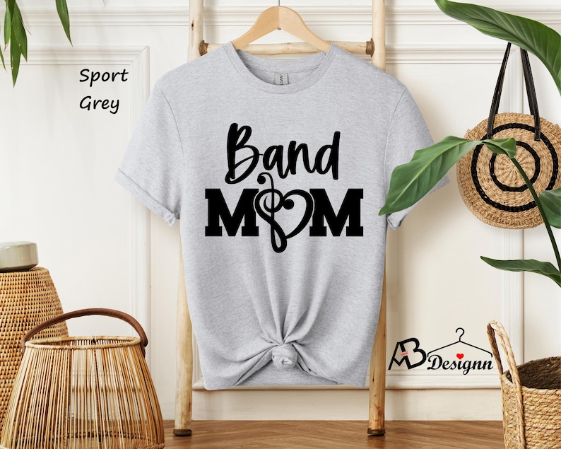 May include: A grey t-shirt with the text "Band Mom" in black lettering. A musical note and heart are included in the design.