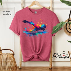 May include: Heather raspberry t-shirt with a colorful graphic of a swimmer in a splash of water.