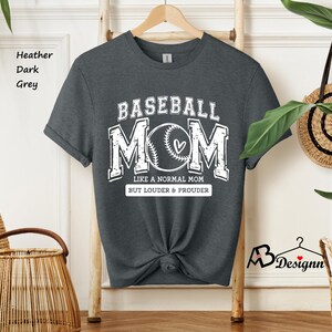 May include: Dark heather grey t-shirt with a white graphic that says "Baseball Mom" with a baseball and heart design. The text below says "Like a normal mom but louder & prouder".