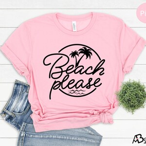 Może przedstawiać: R&oacute;żowa koszulka z czarnym kołem z napisem "Beach Please" z palmami i falami.