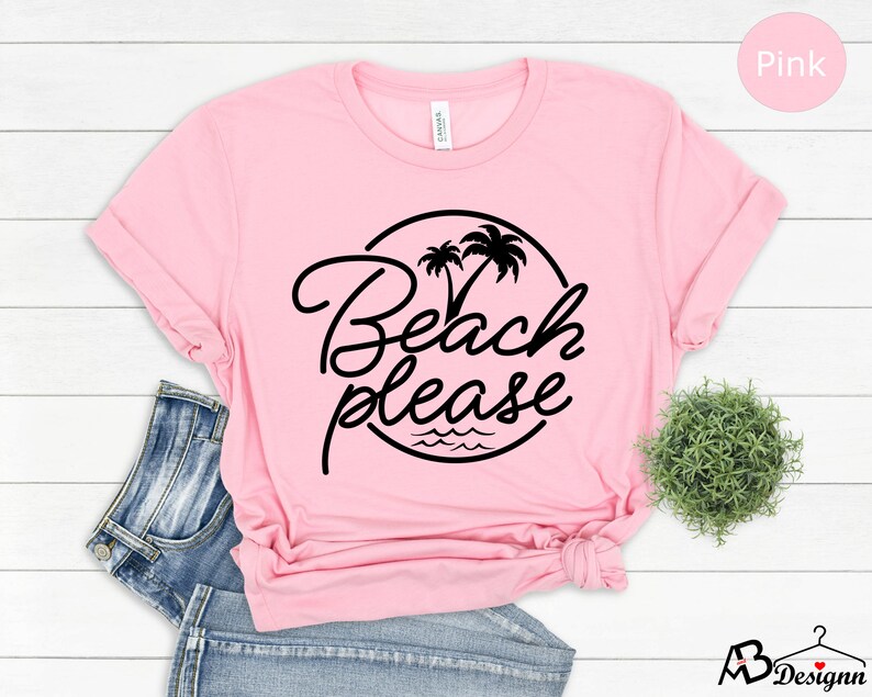 Może przedstawiać: R&oacute;żowa koszulka z czarnym kołem z napisem "Beach Please" z palmami i falami.