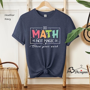 May include: A heather navy blue t-shirt with the text "Do Math Not Magic Show your work" in a colorful rainbow font.