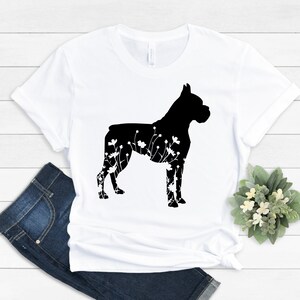 K&ouml;nnte beinhalten: Wei&szlig;es T-Shirt mit einer schwarzen Silhouette eines Boxerhundes mit floralen Details.
