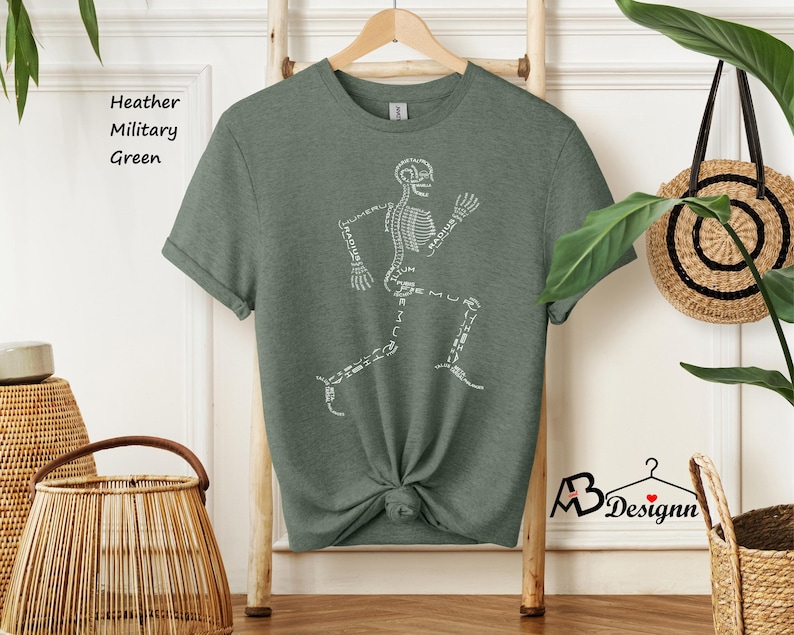 May include: A heather military green t-shirt with a white skeleton running design. The skeleton is labeled with the names of the bones.