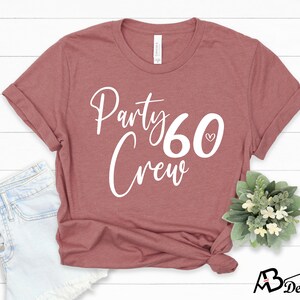 May include: A maroon t-shirt with the text "Party 60 Crew" in white lettering. A small white heart is next to the number 60.