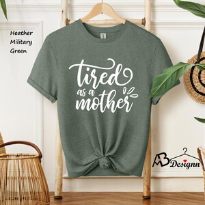May include: A green t-shirt with the text "tired as a mother" in white lettering.