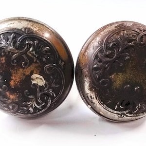 May include: Two antique silver door knobs with ornate floral designs.