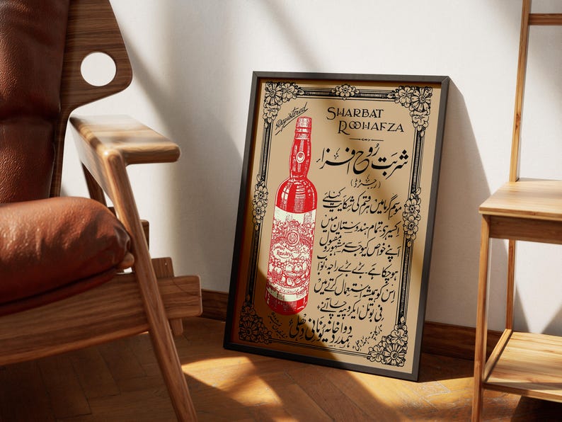 May include: A vintage framed poster advertising Sharbat Rooh Afza, a popular Indian beverage. The poster features a red bottle with a gold label and Urdu text.