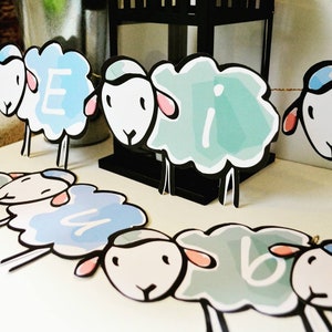 Peut inclure: Une guirlande de moutons bleus et blancs avec les lettres "E I B" sur les moutons. La guirlande est en papier et est parfaite pour une fête prénatale ou un anniversaire.