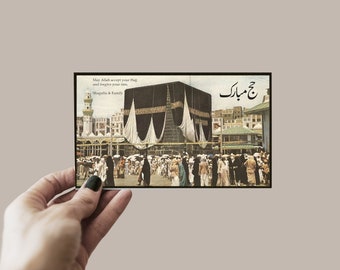 May include: A vintage postcard featuring a black and white photo of the Kaaba in Mecca, Saudi Arabia. The text on the postcard reads "May Allah accept your Hajj and forgive your sins. Shagufta & Family" and "Hajj Mubarak".