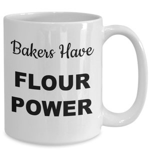 May include: White ceramic mug with black text that reads "Bakers Have Flour Power".