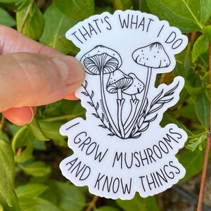 A premium 3 inch by 2 inch die-cut vinyl sticker. The sticker graphic is a black and white cluster of mushrooms with black text. The text says That's What I Do. I Grow Mushrooms And Know Things. Our stickers are waterproof/UV resistant.