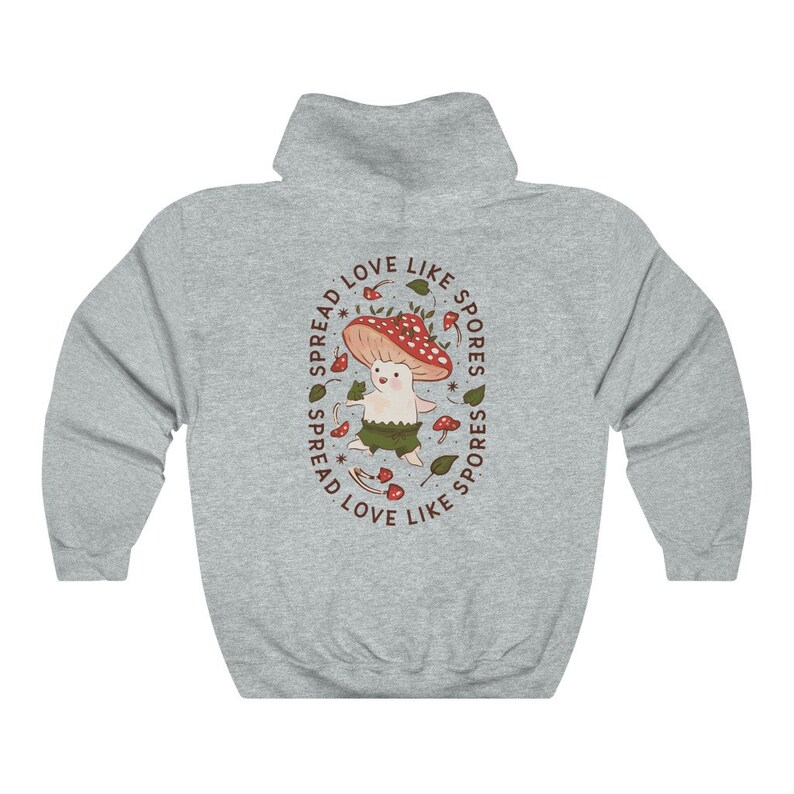 The back of a long-sleeved ash color hoodie. It has an art imprint of the colorful mushroom Amanita Muscaria in cartoon form and the words Spread Love Like Spores around the art.
