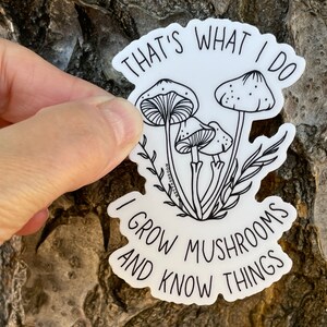 A premium 3 inch by 2 inch die-cut vinyl sticker. The sticker graphic is a black and white cluster of mushrooms with black text. The text says That's What I Do. I Grow Mushrooms And Know Things. Our stickers are waterproof/UV resistant.