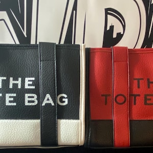 May include: Two tote bags, one black and white and one red and black, with the text "THE TOTE BAG" printed on the front.