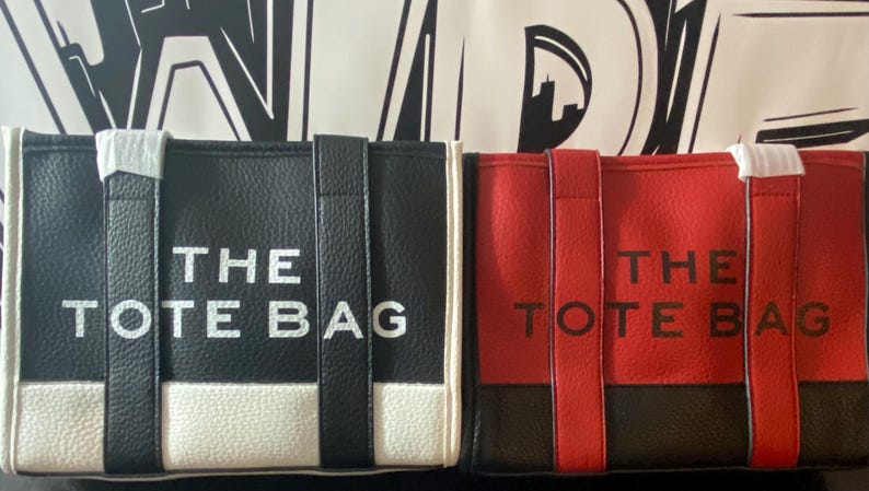 May include: Two tote bags, one black and white and one red and black, with the text "THE TOTE BAG" printed on the front.