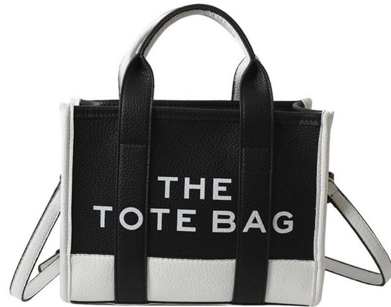May include: Black and white tote bag with the text "THE TOTE BAG" printed in white on the front.