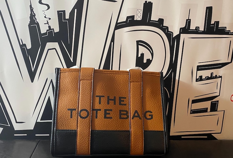 May include: A brown and black tote bag with the text "THE TOTE BAG" printed on the front.