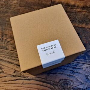 May include: A brown cardboard box with a white label that says "You have been expecting me. Open Me."