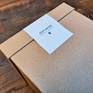 May include: A brown cardboard box with a white label that says "JUST MAYBE VINTAGE MARKET" with a small heart symbol.