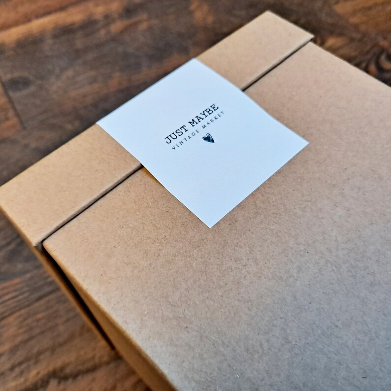 May include: A brown cardboard box with a white label that says "JUST MAYBE VINTAGE MARKET" with a small heart symbol.