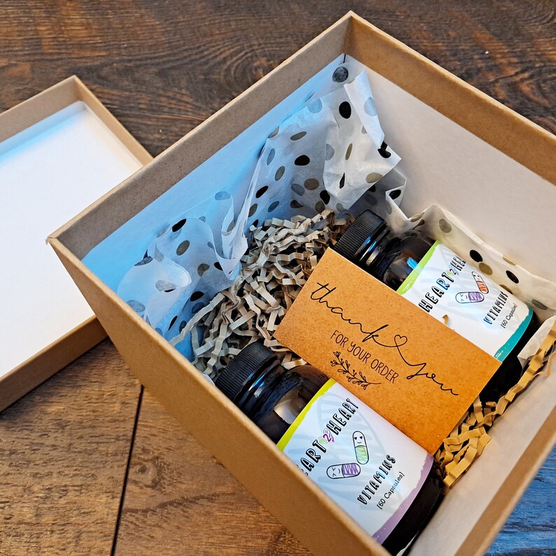 May include: A brown cardboard box with a thank you note and two bottles of vitamins. The bottles are labeled "Art 2 Heart Vitamins" and "Heart Help Vitamins".