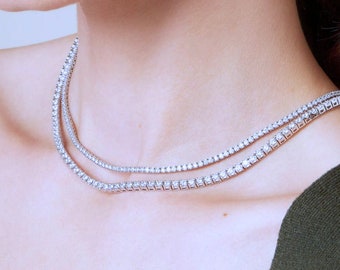 May include: A double row diamond tennis necklace with a silver chain. The necklace is worn by a person with fair skin.
