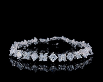 May include: A silver bracelet with a row of clear cubic zirconia stones. The stones are set in a variety of shapes, including round, square, and rectangular.