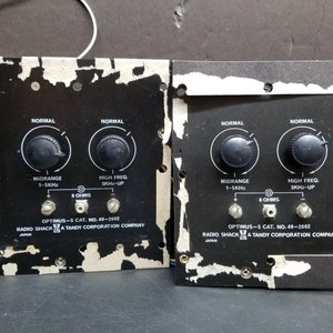 以下が含まれることがあります： 「ノーマル」、「ミッドレンジ 1-5KHz」、「ハイ・フリーク SKHz-UP」とラベル付けされたノブが付いた黒いスピーカークロスオーバーパネル2枚。パネルには「Optimus-5 Cat. No. 40-2002 Radio Shack A Tandy Corporation Company」とラベル付けされています。