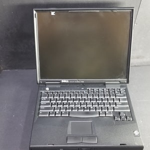 May include: A black Dell Inspiron laptop with a black screen, keyboard, and touchpad. The laptop is closed.