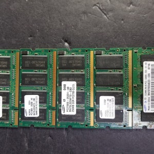 Pode incluir: Quatro placas de circuito verde com texto preto e etiquetas. As etiquetas incluem o texto "SAMSUNG", "KOREA", "PC21005", "PC27005", "M47013224FTO", "M47076554E23", "256 MB", "512 MB", "DDR", "PC2-5300", "PC2700", "CL2.5", "CL2", "Fabricado na China", "0716", "CE6", "2Rx16", "555-12-43", "25331", "25330", "A0", "CB3", "CNO", "A", "0332", "0324", "0448", "K4H5616380", "K4H561638F", "TCB0", "TCB3", "322", "9nt", "SHYS".