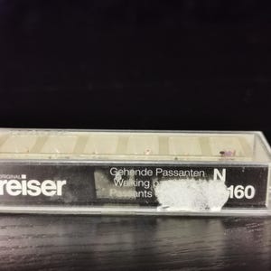 May include: A clear plastic box containing a set of miniature figures of walking pheasants. The box is labelled "Original Preiser" and "Gehende Passanten N 160".