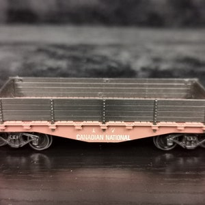 May include: A pink toy train car with a black wooden bed and the words "Canadian National" printed on the side.