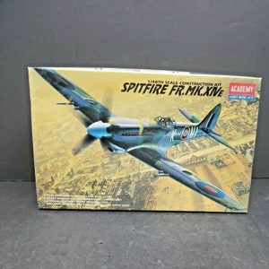 Puede incluir: Un kit de maqueta de plástico a escala 1/48 de un avión de combate Supermarine Spitfire FR.Mk.XIVe azul y verde. El arte de la caja muestra el avión volando sobre una ciudad.