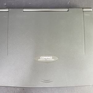 May include: A gray Compaq Armada 1660DMT laptop computer. The laptop is closed and has a silver Compaq logo on the front.