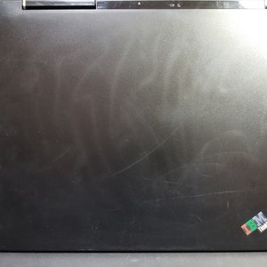 Może przedstawiać: Czarny laptop z srebrnym logo IBM ThinkPad w prawym dolnym rogu.