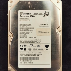 May include: A silver hard drive with the Seagate Barracuda ATA IV logo and the text "Model ST320011A". The drive has a serial number, product number, and other technical information printed on the label. The drive is labelled as a product of Singapore.