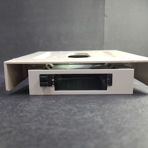 May include: A beige plastic hard drive bay with a black connector and a gray metal hard drive inside.