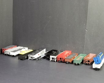 Puede incluir: Una colección de 11 vagones de tren en miniatura, que incluyen una variedad de vagones de caja, tolvas y vagones de carga. Los vagones están hechos de plástico y metal y están pintados en varios colores, incluyendo negro, rojo, azul, verde y amarillo. Algunos de los vagones tienen letras en ellos, como "Lemon Valley" y "R.R."