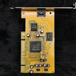 May include: A yellow printed circuit board with a black connector and a chip labeled "Silicon Image SATA Link Sil3112ACT144 023145.123 0345 1.21".