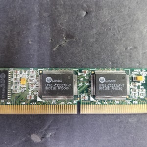 May include: A green circuit board with two chips labeled "UMC UM61 43232AF-7 9631SE RM5C60". The board is labeled "MADE IN TAIWAN SYNC CACHE MODULE VER 1.8".