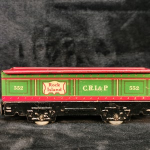 May include: A red and green toy train car with the words "Rock Island" and "C.R.I.&P." printed on the side. The car is numbered "552".