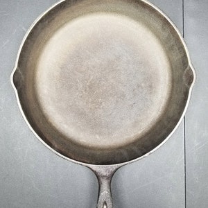 May include: A black cast iron skillet with a single handle. The skillet is empty and has a smooth, slightly textured surface.