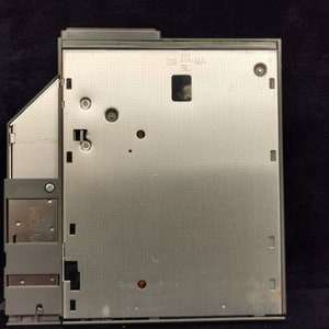 May include: A silver-colored optical drive with the text "OS_JTL_MA_SL" printed on the front.