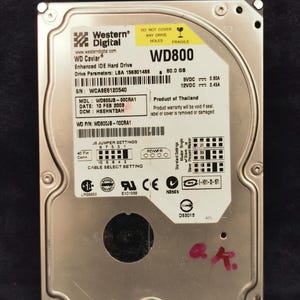 May include: A silver hard drive with the label "Western Digital WD Caviar" and the model number "WD800". The drive has a capacity of 80.0 GB and is a product of Thailand. The label also includes the serial number, model number, date, and other technical specifications.