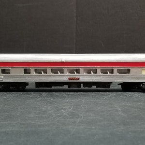 May include: A silver and red passenger train car model with the number "7702" printed on the side.
