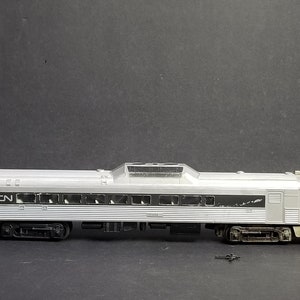 Puede incluir: Un vagón de tren modelo plateado con las letras "CN" en el lateral. El vagón tiene varias ventanas y un techo plateado con una sección elevada en el medio.