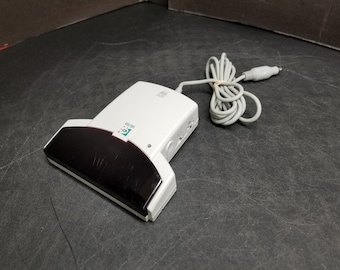 May include: A white and black card reader with a green logo that says "Logitech". The reader has a black scanner and a white cord.