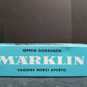 May include: A blue box with white text that reads "Öppen Godsvagn" and "MÄRKLIN" in a large font. Below the logo, it reads "Vagone Merci Aperto".